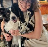 Amanda wearing glasses, in black and white, along with her dog, a border collie